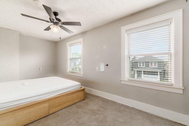 carpeted bedroom featuring ceiling fan and a textured ceiling