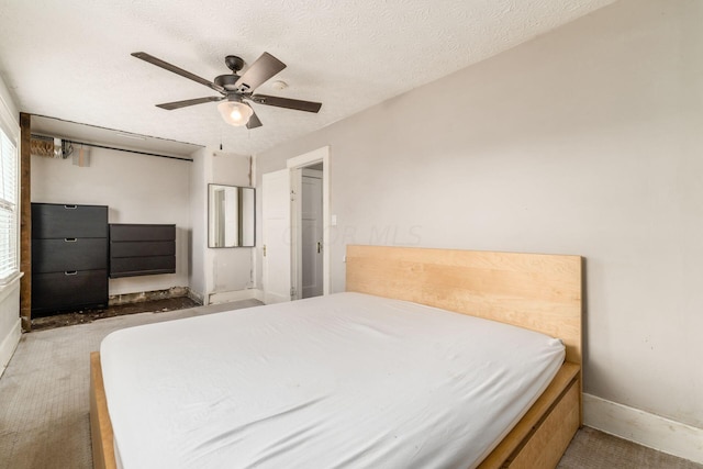 carpeted bedroom featuring ceiling fan and a textured ceiling