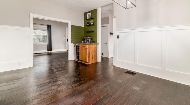 interior space featuring a textured ceiling, dark hardwood / wood-style floors, and beverage cooler