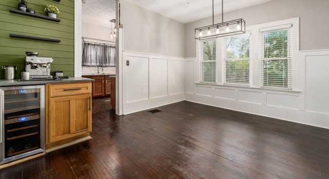 unfurnished dining area with dark hardwood / wood-style flooring, indoor bar, beverage cooler, and a textured ceiling