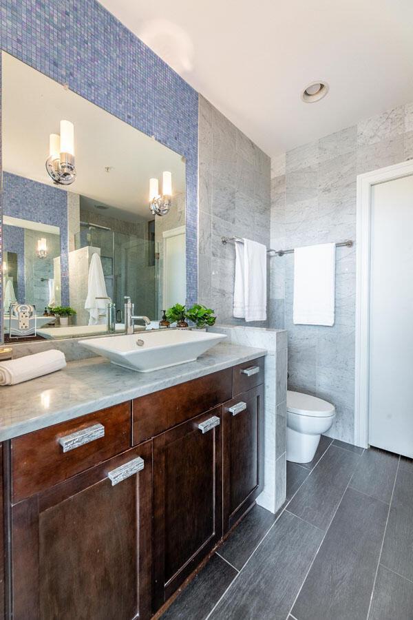 bathroom featuring vanity, toilet, tile walls, and a shower with shower door