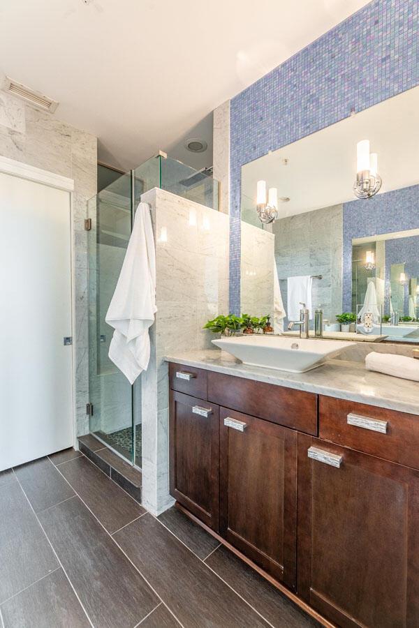 bathroom with a shower with door, vanity, and tile walls