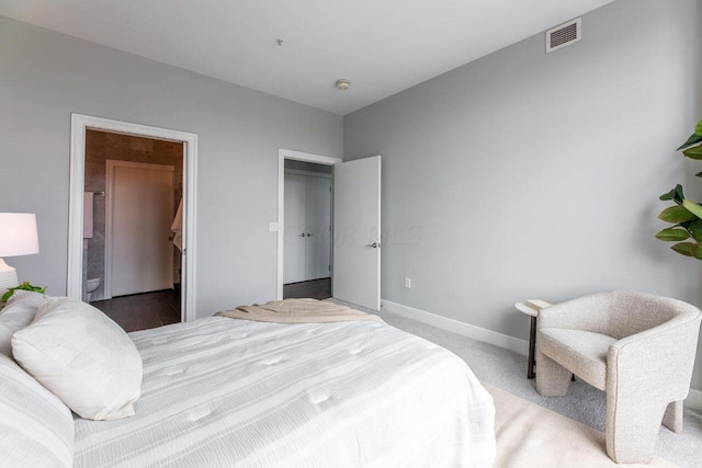 bedroom with a spacious closet, carpet floors, and ensuite bathroom