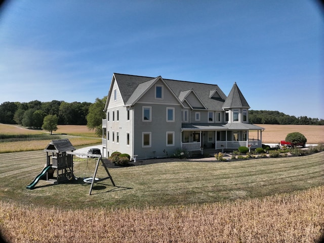 back of house featuring covered porch, a yard, and a playground