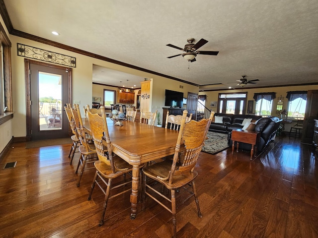 dining area featuring ceiling fan, dark wood-type flooring, a textured ceiling, and ornamental molding