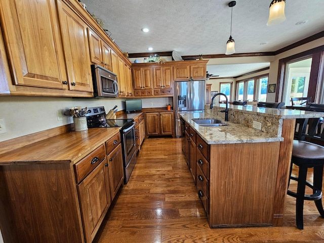 kitchen featuring sink, hanging light fixtures, dark hardwood / wood-style flooring, a textured ceiling, and appliances with stainless steel finishes