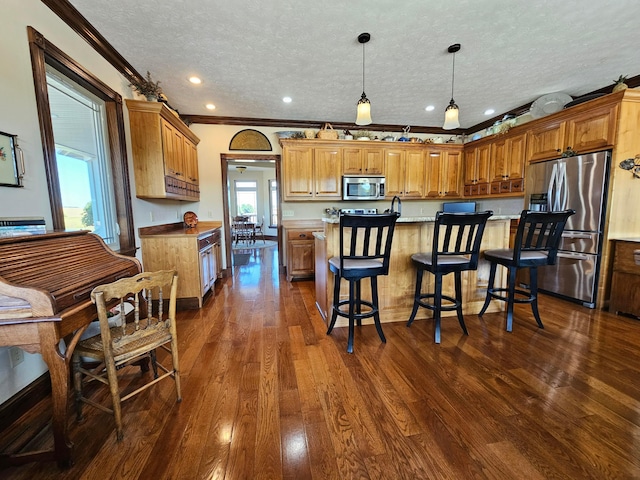 kitchen with a textured ceiling, dark hardwood / wood-style floors, ornamental molding, and stainless steel appliances