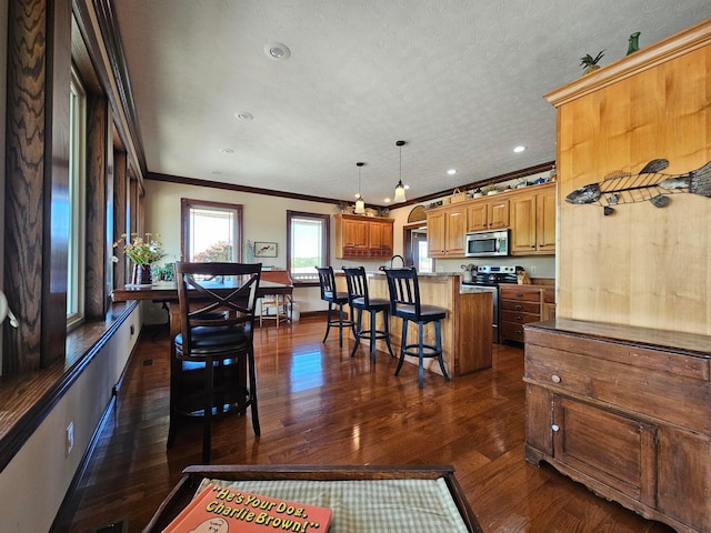 kitchen with a breakfast bar, a center island, dark wood-type flooring, crown molding, and stainless steel appliances