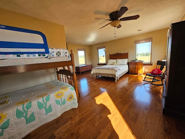 bedroom with ceiling fan, dark hardwood / wood-style flooring, and a textured ceiling