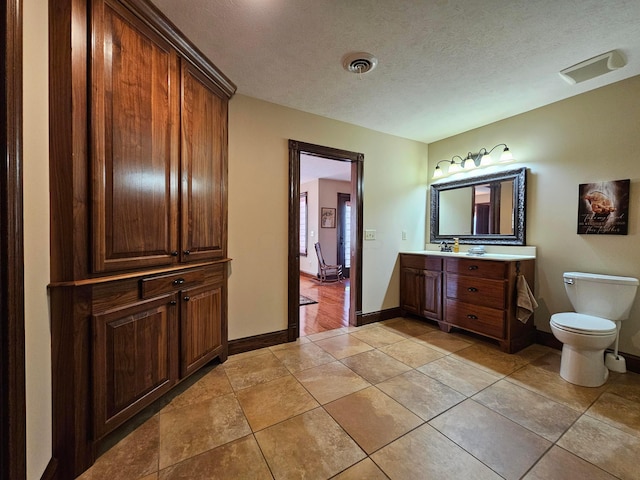 bathroom featuring tile patterned floors, vanity, toilet, and a textured ceiling