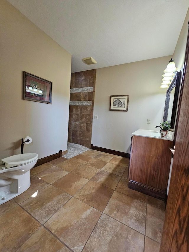 bathroom with a tile shower, vanity, and toilet