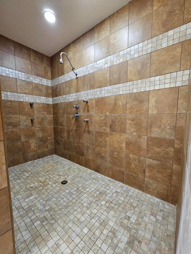 bathroom with a tile shower and a textured ceiling