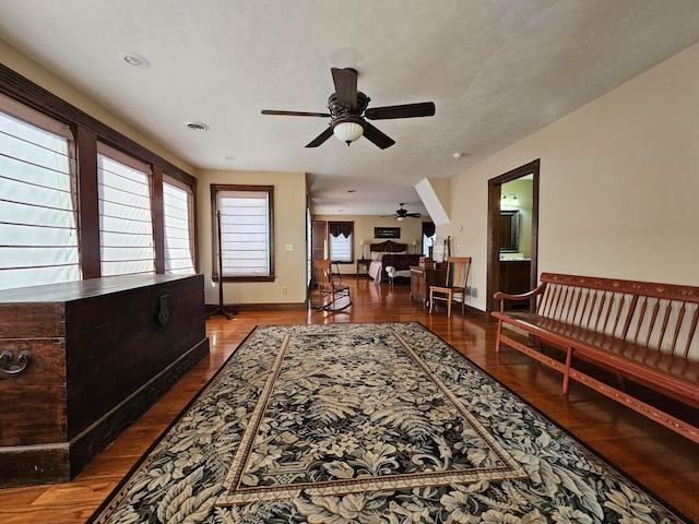 living room featuring hardwood / wood-style floors, ceiling fan, and a textured ceiling