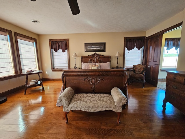 bedroom with multiple windows, ceiling fan, hardwood / wood-style floors, and a textured ceiling