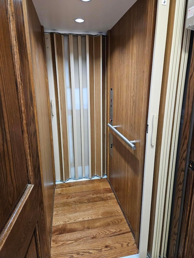 interior space featuring hardwood / wood-style flooring, elevator, and wood walls