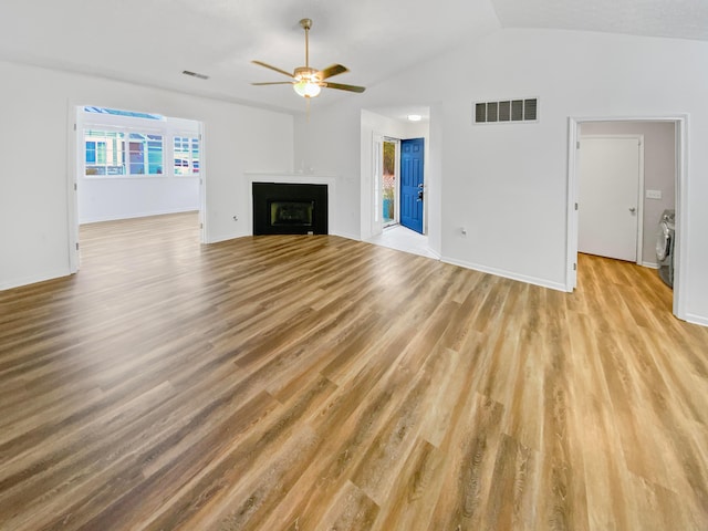 unfurnished living room featuring washing machine and dryer, ceiling fan, light hardwood / wood-style flooring, and lofted ceiling