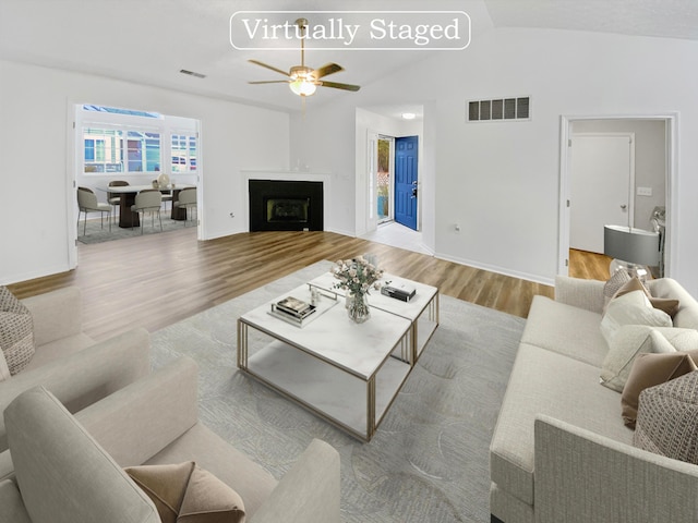 living room with ceiling fan, light hardwood / wood-style flooring, and lofted ceiling