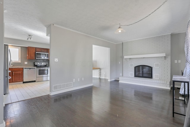 unfurnished living room with a fireplace, a textured ceiling, hardwood / wood-style flooring, and crown molding