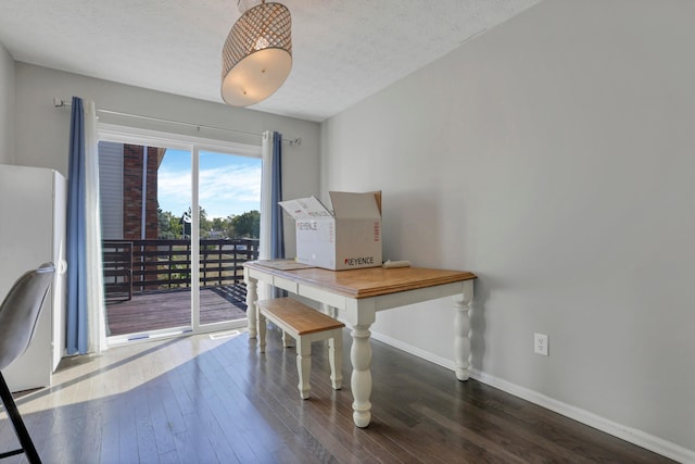 dining space with dark wood-type flooring and a textured ceiling