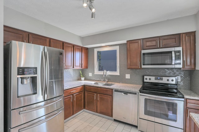 kitchen featuring light stone counters, sink, stainless steel appliances, and tasteful backsplash