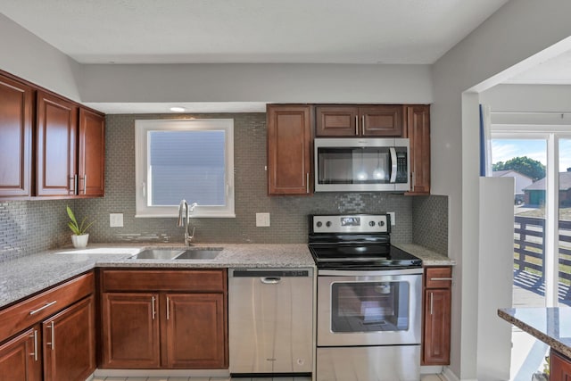 kitchen featuring decorative backsplash, sink, light stone counters, and appliances with stainless steel finishes