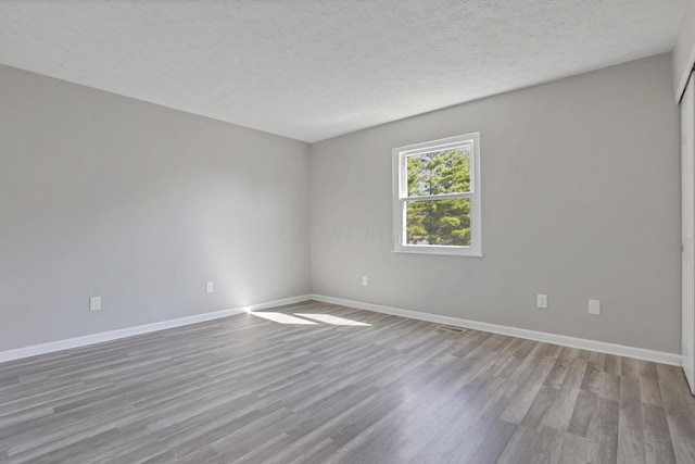 unfurnished room featuring a textured ceiling and light hardwood / wood-style flooring