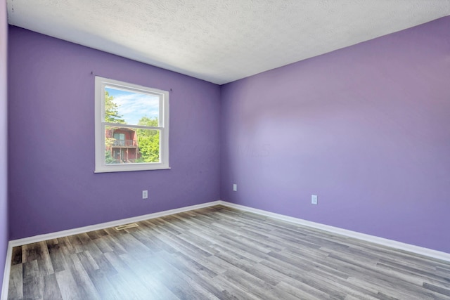 unfurnished room with a textured ceiling and light hardwood / wood-style flooring