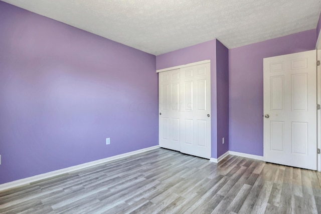 unfurnished bedroom featuring a textured ceiling, light wood-type flooring, and a closet