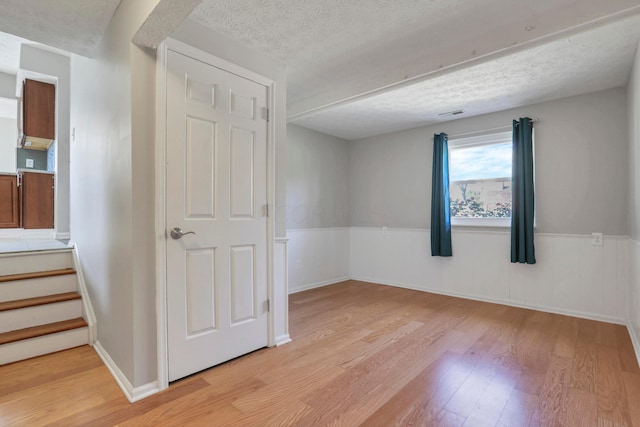 unfurnished room with a textured ceiling and light hardwood / wood-style flooring