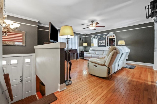 living room with ceiling fan with notable chandelier, light hardwood / wood-style floors, and crown molding