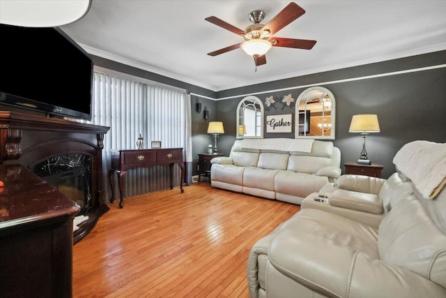 living room featuring hardwood / wood-style floors, ceiling fan, a fireplace, and crown molding