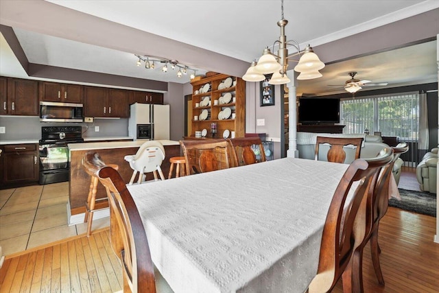 dining area featuring light wood finished floors and ceiling fan with notable chandelier