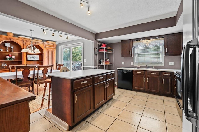 kitchen featuring a center island, light tile patterned floors, light countertops, dark brown cabinets, and dishwasher