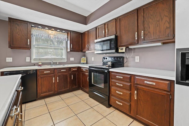 kitchen featuring light countertops, a sink, black appliances, and light tile patterned floors