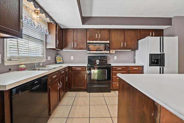 kitchen featuring light tile patterned floors, a sink, dark brown cabinets, light countertops, and black appliances