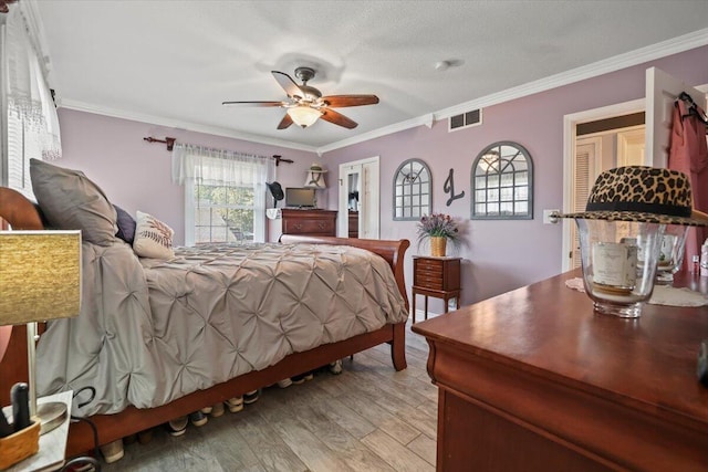 bedroom featuring light wood finished floors, ceiling fan, visible vents, and crown molding