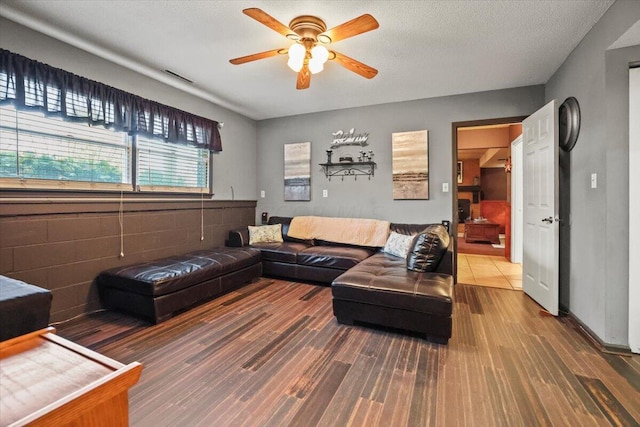 living room featuring hardwood / wood-style flooring, ceiling fan, and a textured ceiling