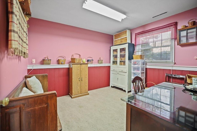 carpeted office featuring a wainscoted wall, visible vents, and wood walls