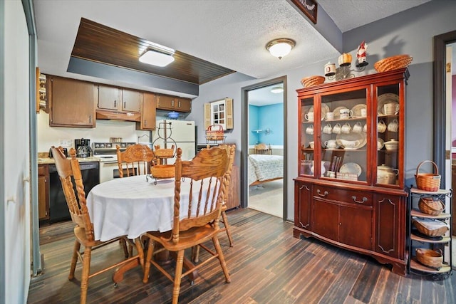 dining area featuring dark wood-type flooring and a textured ceiling