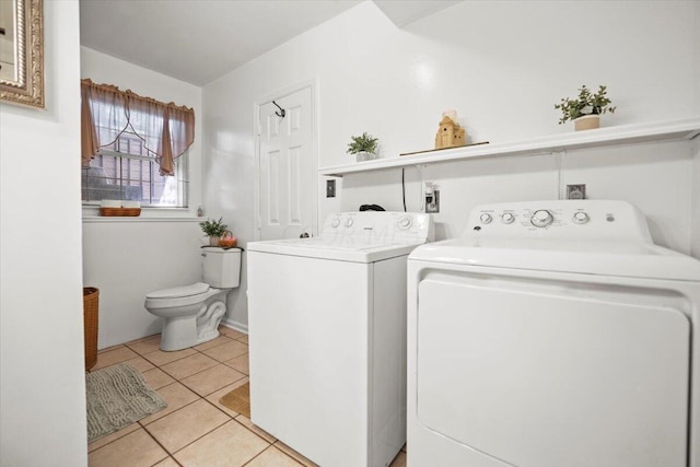 clothes washing area with washer and clothes dryer and light tile patterned floors