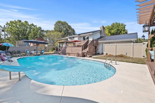 view of pool with a fenced in pool, a patio area, a deck, a water slide, and a fenced backyard