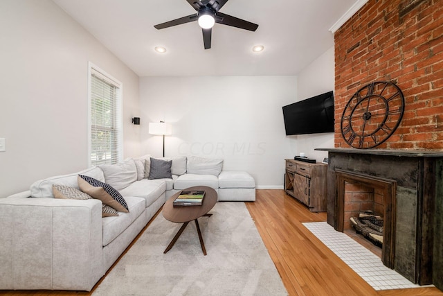 living room featuring a fireplace, light hardwood / wood-style floors, and ceiling fan