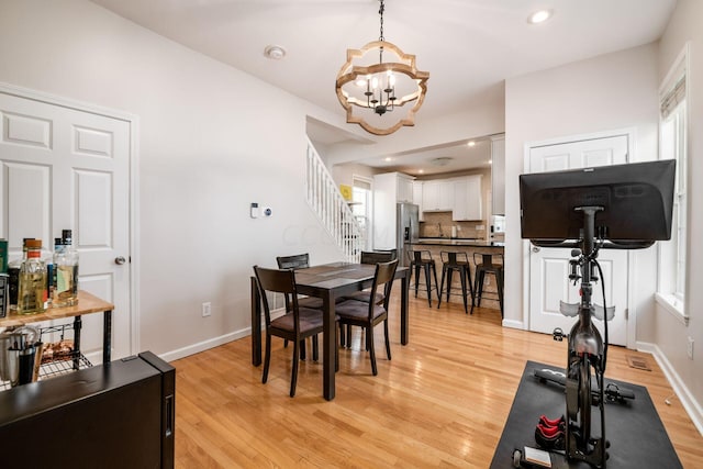 dining space with light hardwood / wood-style flooring and an inviting chandelier