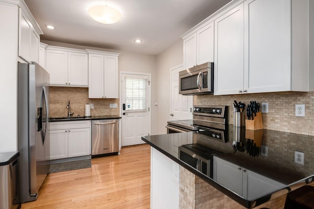 kitchen with light wood-type flooring, white cabinetry, stainless steel appliances, and tasteful backsplash