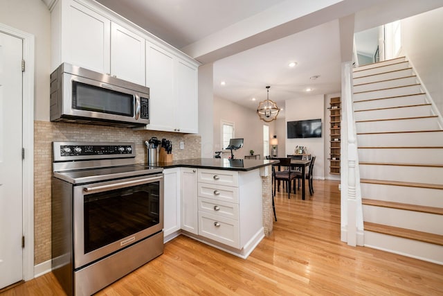 kitchen featuring kitchen peninsula, appliances with stainless steel finishes, light hardwood / wood-style flooring, and white cabinetry