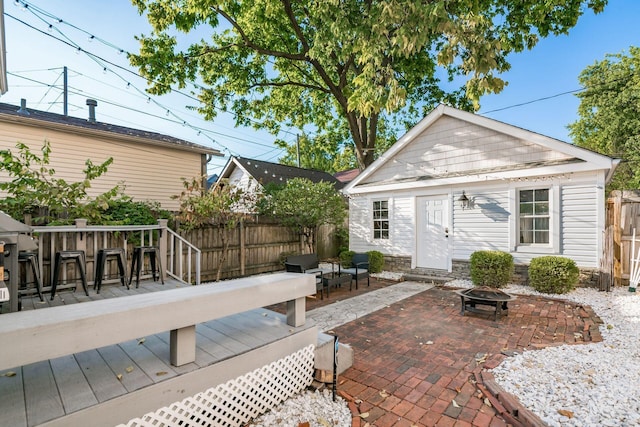 back of property featuring an outbuilding, a bar, a deck, and an outdoor fire pit