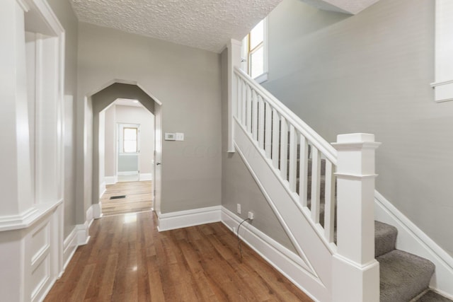 stairs with a textured ceiling and hardwood / wood-style flooring