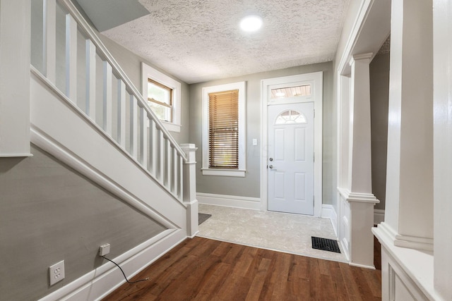 foyer entrance with a textured ceiling and dark hardwood / wood-style floors