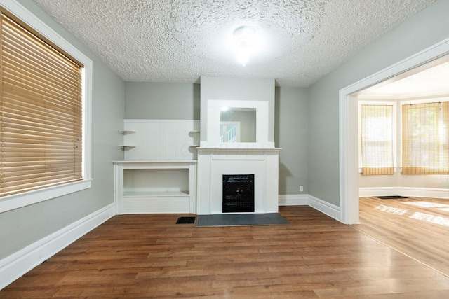 unfurnished living room featuring hardwood / wood-style floors and a textured ceiling