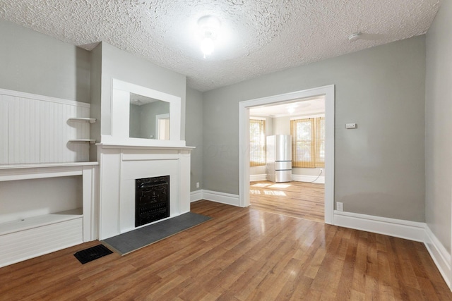 unfurnished living room featuring wood-type flooring and a textured ceiling